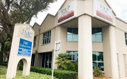 Located at 2201 4th St. N. in St. Petersburg, this two-story office building houses JMC Communities and a dentist, with large signs and glass windows, surrounded by greenery and a sidewalk—ideal for lease renewal opportunities.