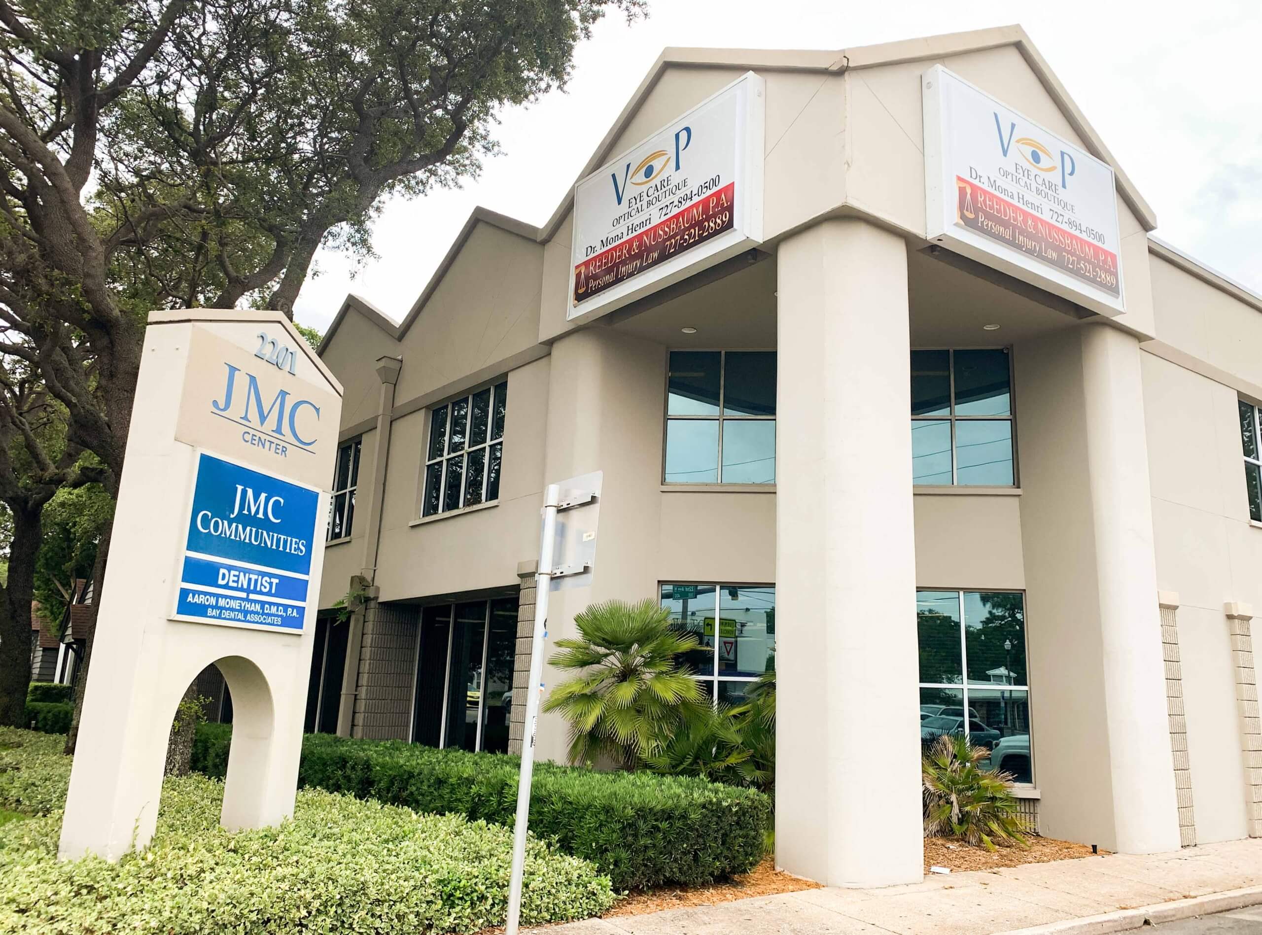 Located at 2201 4th St. N. in St. Petersburg, this two-story office building houses JMC Communities and a dentist, with large signs and glass windows, surrounded by greenery and a sidewalk—ideal for lease renewal opportunities.