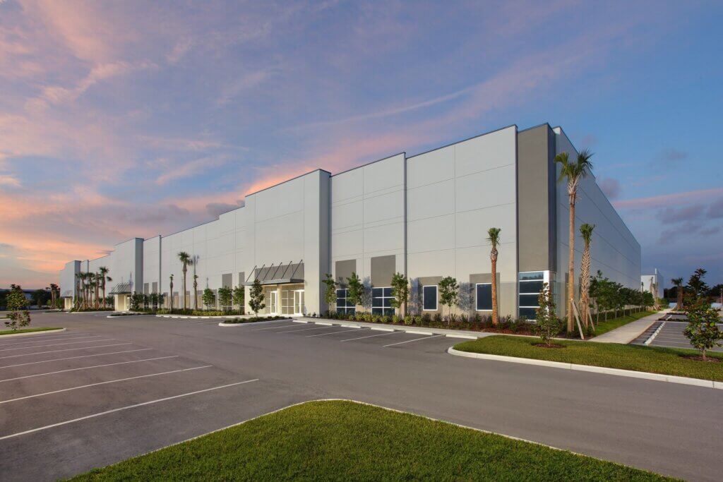 Large, modern warehouse building with tall windows and palm trees at 8515 126th Ave N in Largo, FL, surrounded by an empty parking lot at sunset. Currently leased.