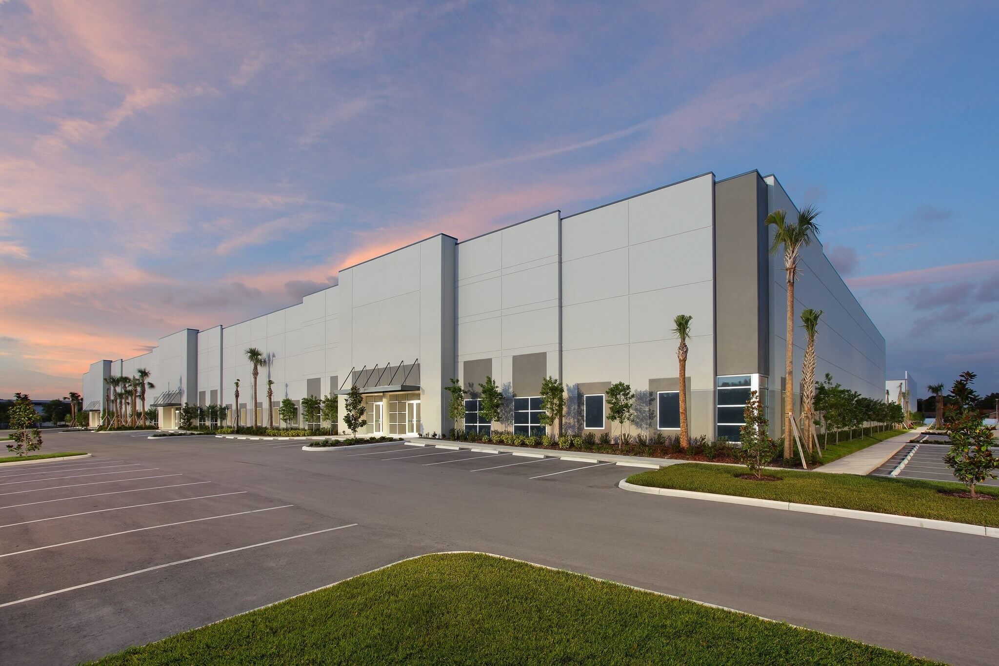 Large, modern warehouse building with tall windows and palm trees at 8515 126th Ave N in Largo, FL, surrounded by an empty parking lot at sunset. Currently leased.