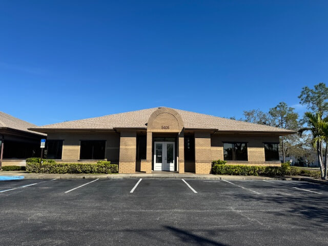 Single-story brick office building on Park Street with large windows, double glass doors, and an empty parking lot under a clear blue St. Petersburg sky—now available to be leased.