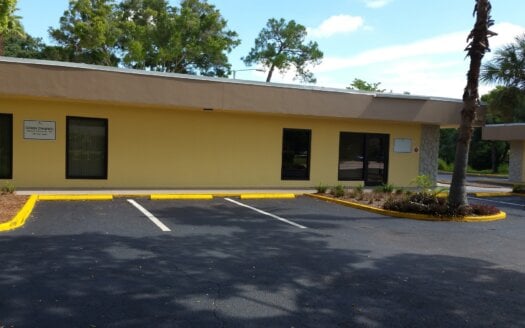 A small, single-story yellow building at 6701 38th Ave. N., St. Petersburg, with two empty parking spaces in front, is surrounded by trees and landscaped areas. This property is currently leased.