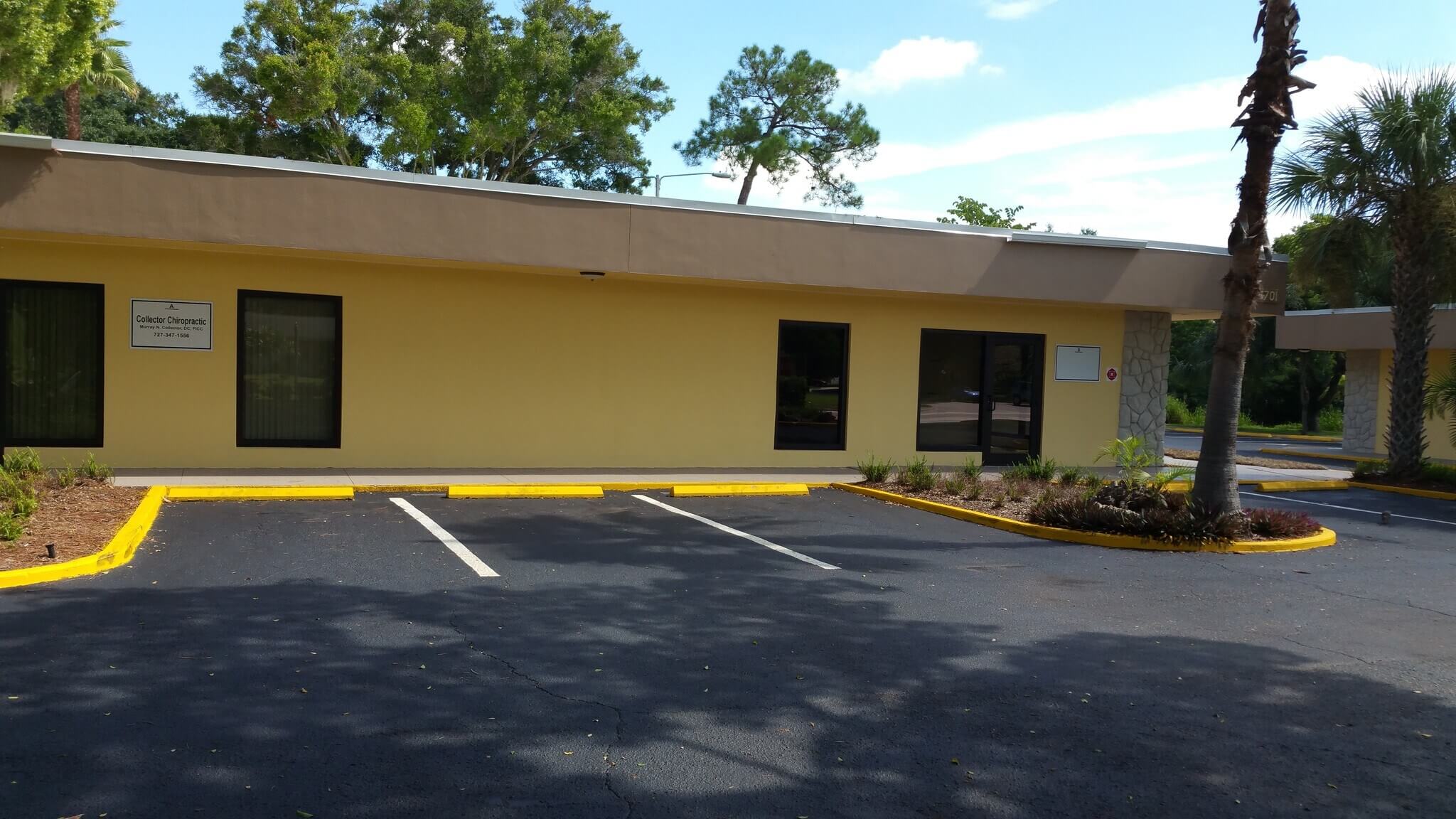 A small, single-story yellow building at 6701 38th Ave. N., St. Petersburg, with two empty parking spaces in front, is surrounded by trees and landscaped areas. This property is currently leased.
