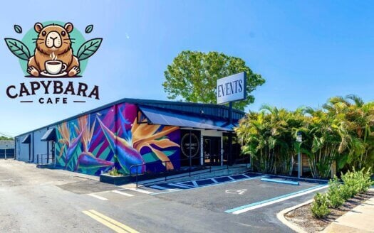 A single-story building at 4703 Park St, St. Petersburg, with a colorful mural and palm trees, featuring signage for "Capybara Cafe" and "Events" under a clear blue sky—recently sold in sunny FL.