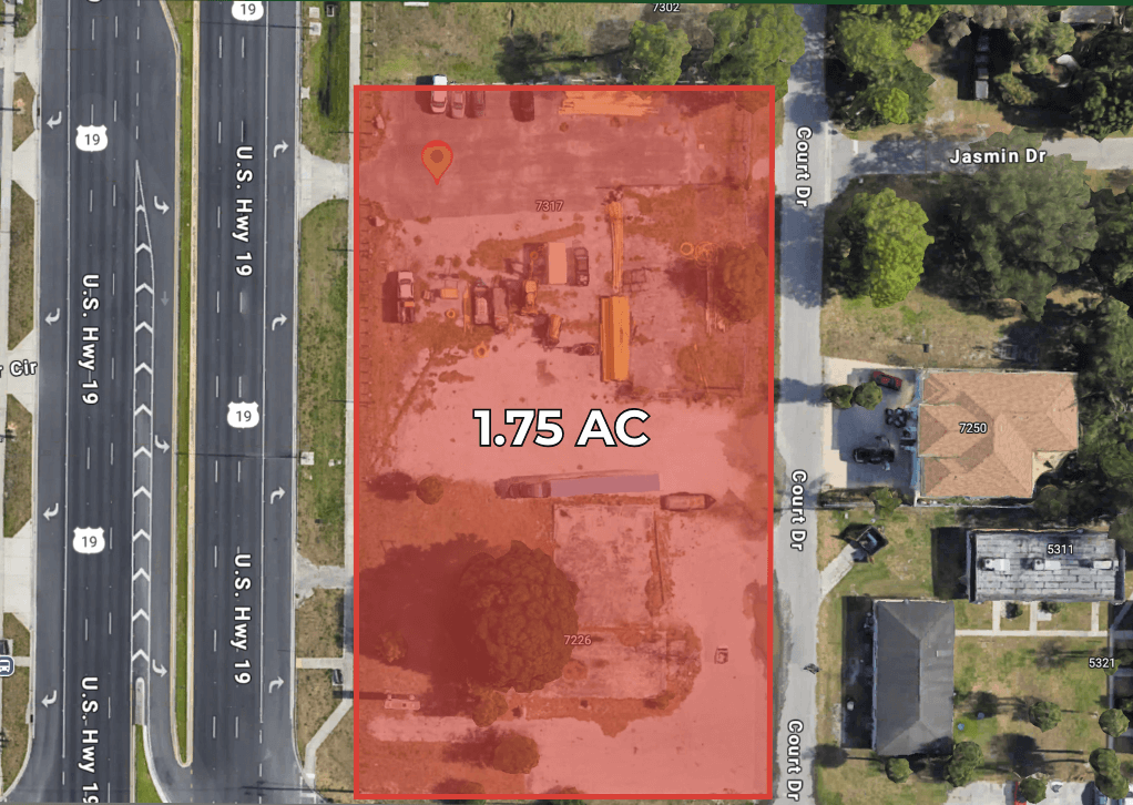 Aerial view of a 1.75-acre lot outlined in red at the corner of US Hwy 19 N and Count Dr in New Port Richey, FL, with surrounding streets and buildings visible.